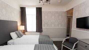 A hotel room with two beds, a TV, a chair, and a dresser.
