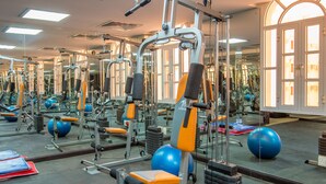 A gym with exercise equipment, mirrors, and a large window. -  Caesar Hotel (Muscat)