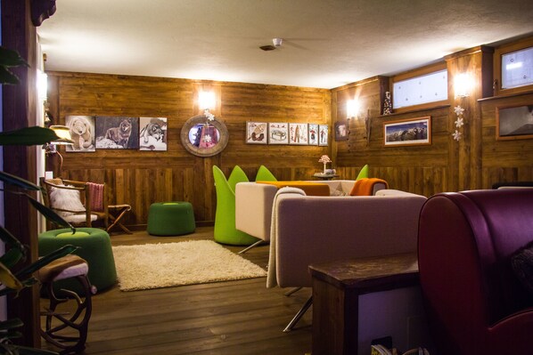 Una habitación acogedora con paredes de madera, un otoman verde y un sofá blanco.