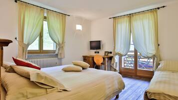 Un dormitorio con cama, escritorio, televisor y vistas al exterior.