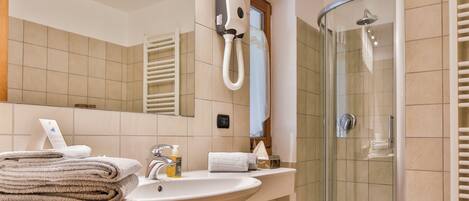 A bathroom with a sink, mirror, towel rack, and a glass-enclosed shower.
