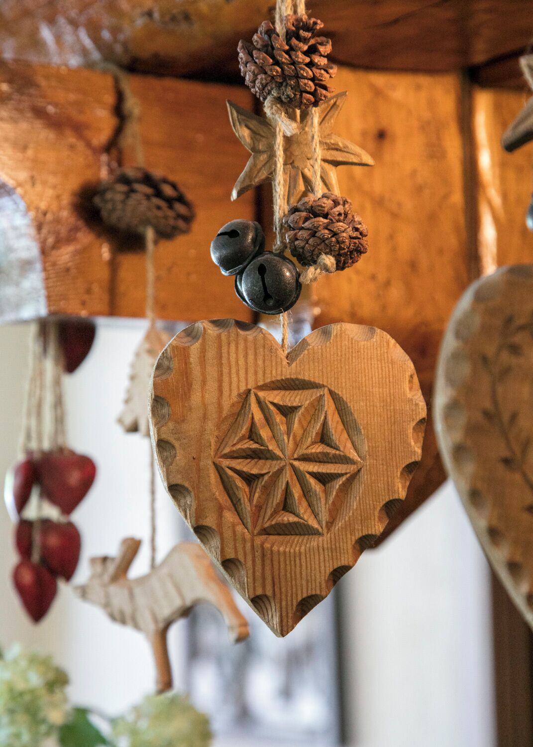 Una decorazione a forma di cuore in legno, con un motivo geometrico, appesa al soffitto in legno.