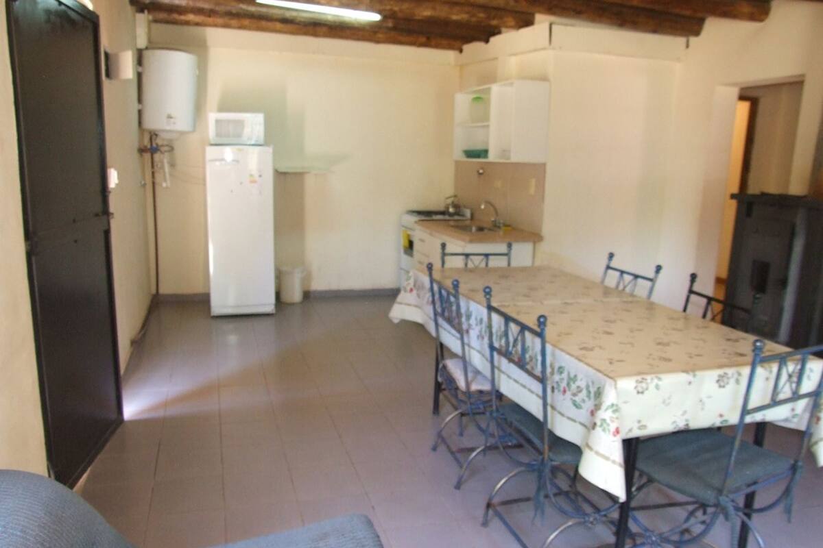 A dining area with a table and chairs, a kitchen with a refrigerator, and a water heater.