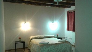 A bedroom with a bed, bedside tables, and a window with curtains. - Cabañas Uspallata (Uspallata)