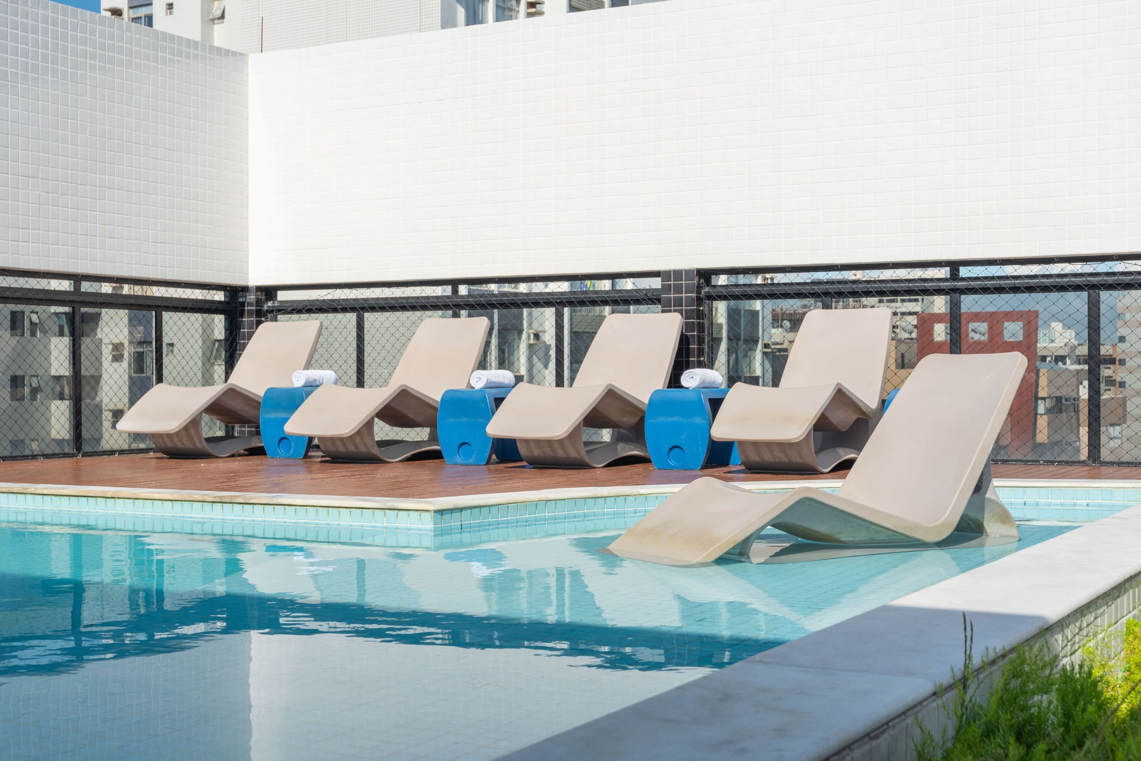 A rooftop pool area with lounge chairs and a clear blue pool.