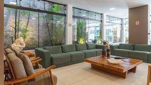 A modern lobby with green sofas, wooden chairs, and a wooden coffee table. - Palms Ponta Verde by Tropicalis (Maceió)