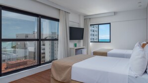 A hotel room with a large window, a bed, a TV, and a small table. - Palms Ponta Verde by Tropicalis (Maceió)