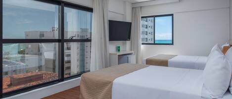 A hotel room with a large window, a bed, a TV, and a small table.