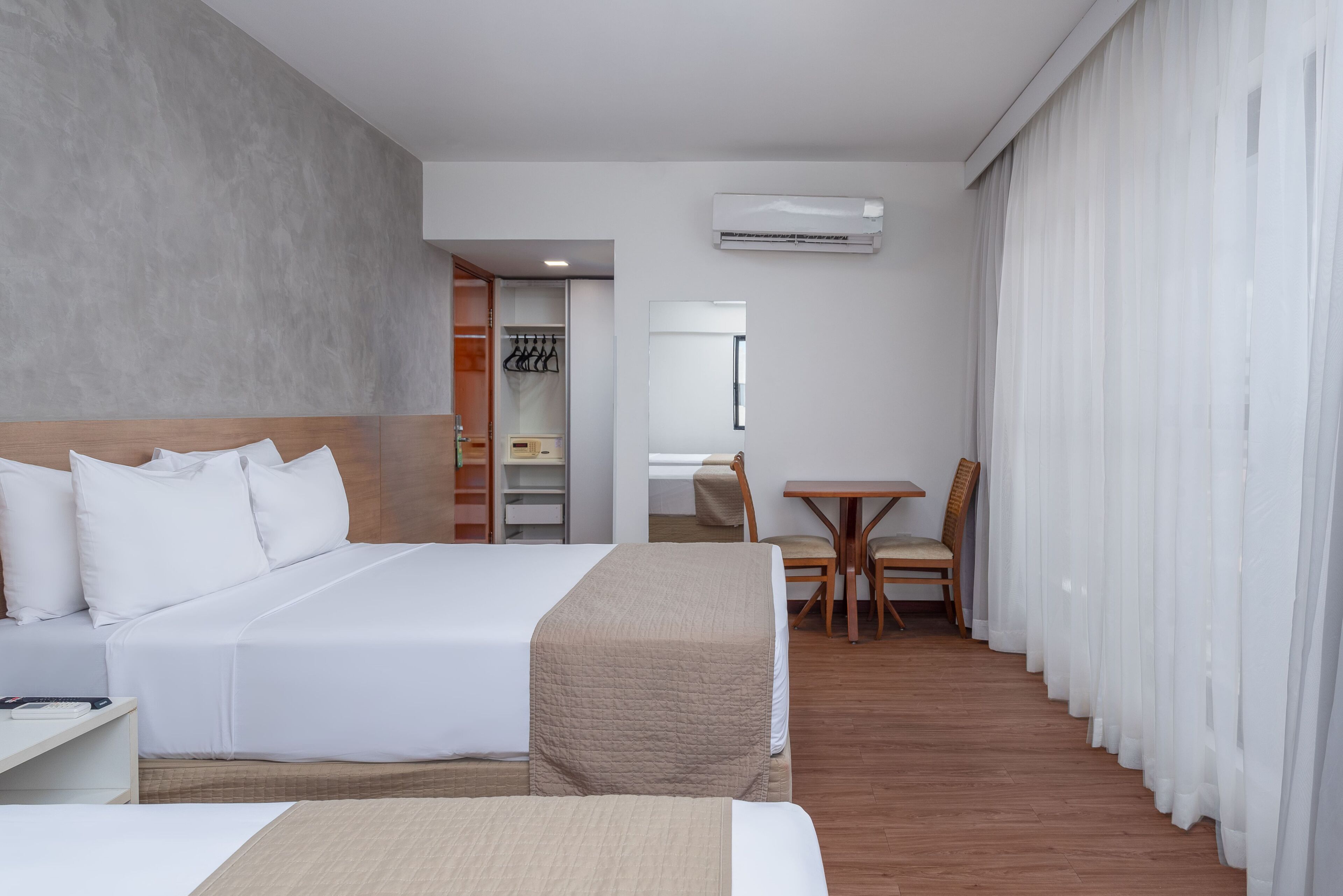 Una habitación de hotel con una cama grande, un escritorio, una silla y un armario.