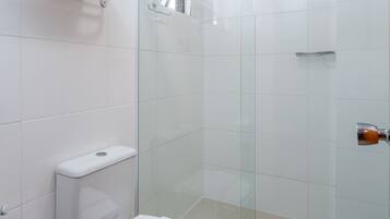 Un baño moderno con cabina de ducha de vidrio, inodoro y perchero para toallas.