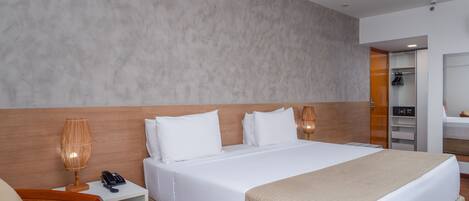 Una habitación de hotel con una cama grande, una mesita de noche con lámpara, una silla y un armario.