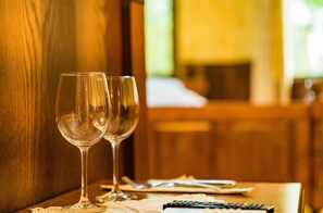 Deux verres à vin vides sont posés sur une table en bois, à côté d’une télécommande et d’une serviette.