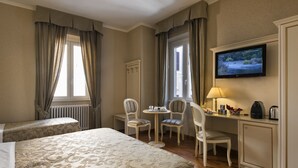 A hotel room with a bed, two chairs, a small table, a television, and a cabinet. - Relais Bocca di Leone (Rome)
