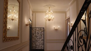 A grand hallway with ornate chandeliers, a decorative iron gate, and a mirrored wall. - Relais Bocca di Leone (Rome)