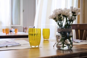 A wooden table with a glass vase containing white flowers and two yellow glass vases.