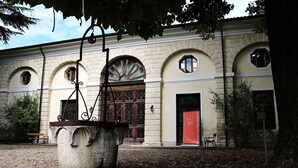A historic building with arched windows and a central door, surrounded by fallen leaves.