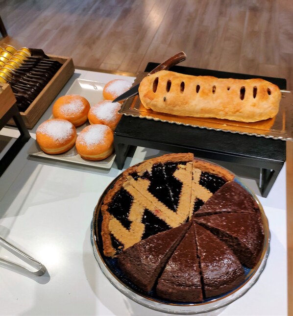 A dessert display with a pie, pastries, and a chocolate-covered item.