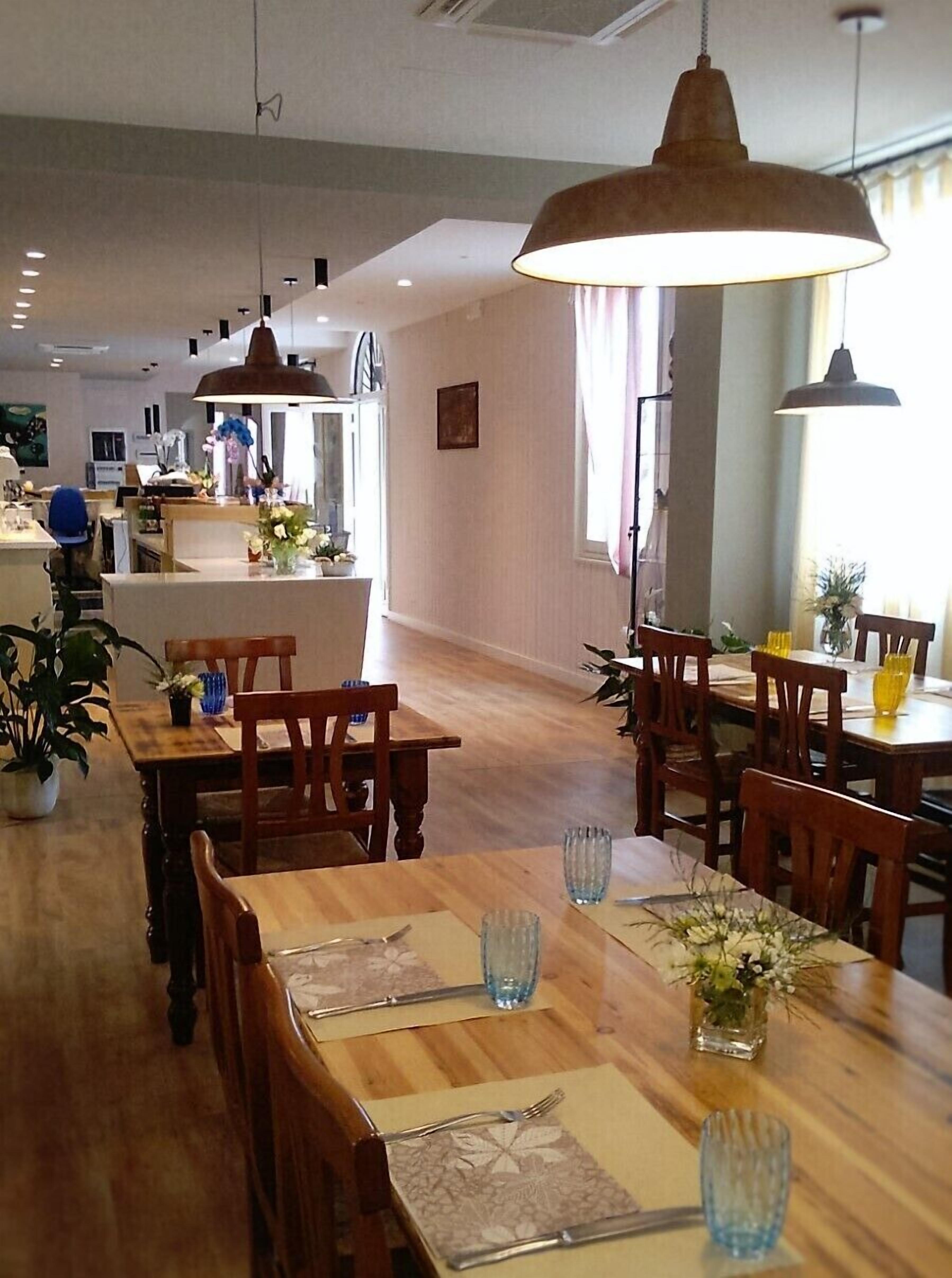 A restaurant with wooden tables and chairs, pendant lighting, and a modern interior design.
