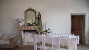 A room with a white table set for four, a fireplace, a mirror, and a wooden door.