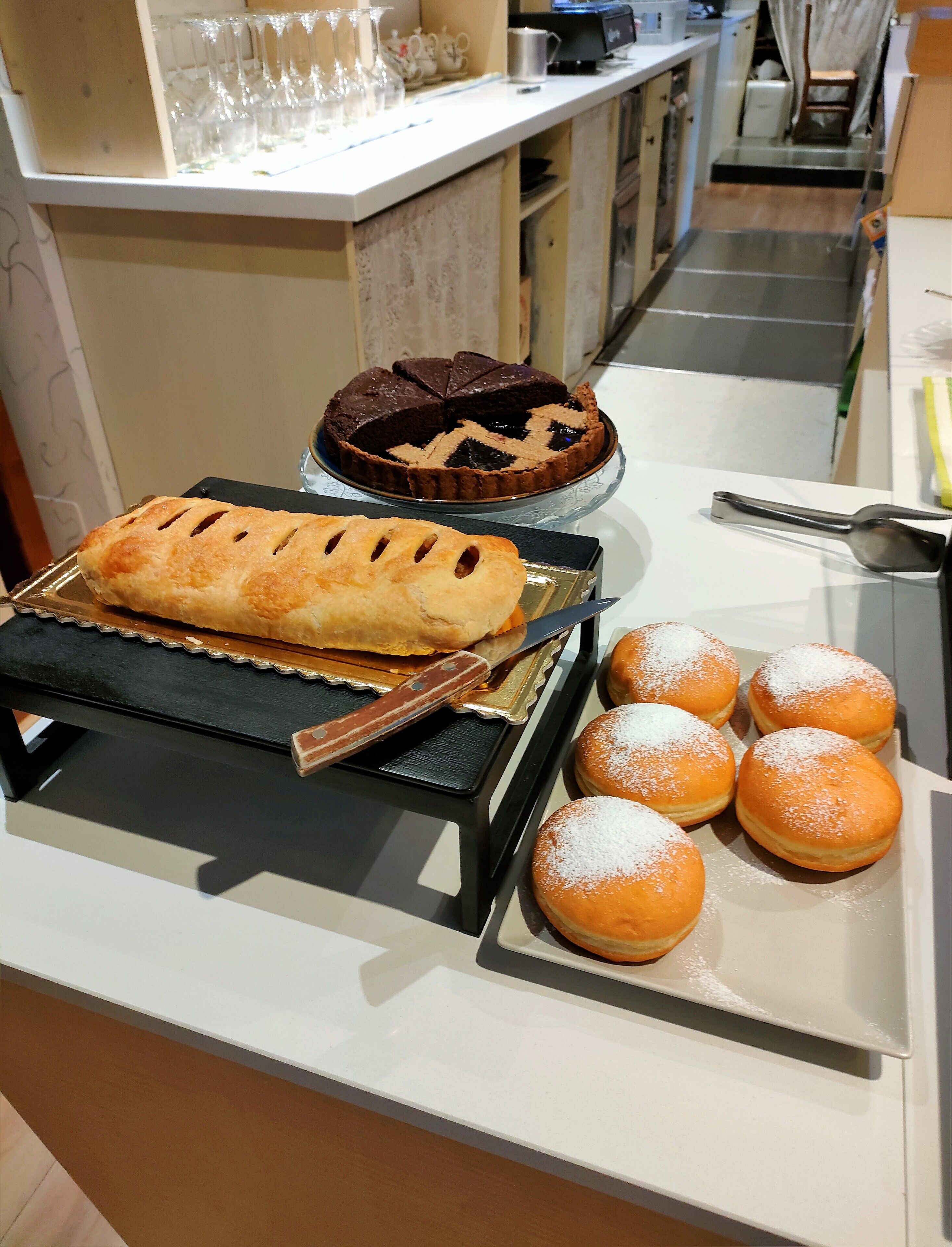 A bakery display with a pie, a loaf, and powdered buns.
