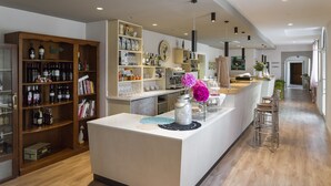 A modern kitchen with a central island, wooden shelves with wine bottles, and a bar area with stools.