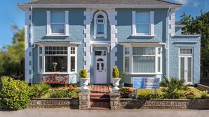 A two-story building with a central entrance, large windows, and a small porch with a bench. - The Richmond Bed & Breakfast (Shanklin)