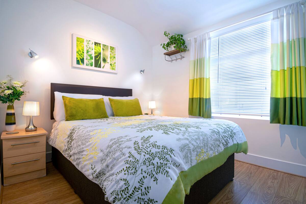 A neatly arranged bedroom with a bed, bedside tables, and a window with curtains.