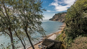 A coastal scene with a beach, a thatched-roof hut, and a cliff overlooking the sea. - The Richmond Bed & Breakfast (Shanklin)