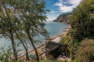 A coastal scene with a beach, a thatched-roof hut, and a cliff overlooking the sea.