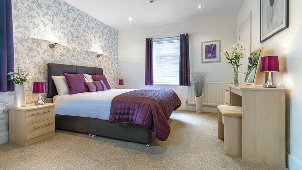 A bedroom with a bed, bedside tables, a desk, and a window with curtains. - The Richmond Bed & Breakfast (Shanklin)