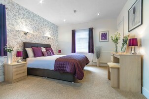 A bedroom with a bed, bedside tables, a desk, and a window with curtains.