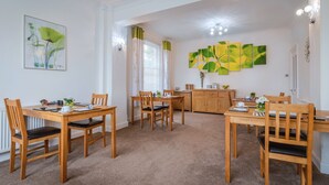 A dining area with wooden furniture, a radiator, and artwork on the walls. - The Richmond Bed & Breakfast (Shanklin)