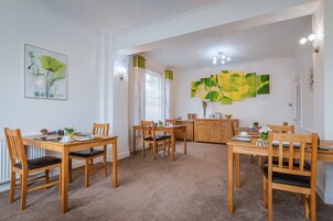 A dining area with wooden furniture, a radiator, and artwork on the walls.