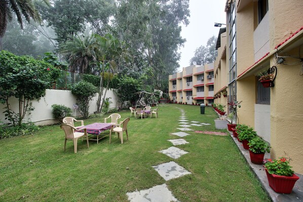 A courtyard with a small table and chairs, surrounded by potted plants and a pathway.