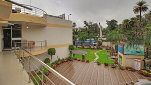 A multi-level hotel with a rooftop deck, indoor seating, and a landscaped garden area. - Hotel Sunset Inn Mount Abu with Swimming Pool (Abu Road)