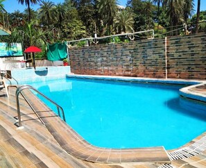 A swimming pool with a wooden deck and a brick wall. - Hotel Sunset Inn Mount Abu with Swimming Pool (Abu Road)