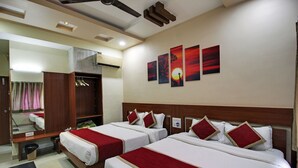 A hotel room with two beds, a wardrobe, a mirror, and artwork on the wall. - Hotel Sunset Inn Mount Abu with Swimming Pool (Abu Road)