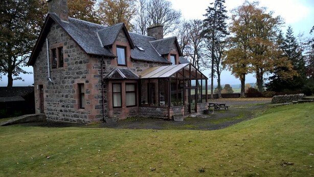 A stone house with a porch and a small garden area. - Balloan House (Muir of Ord)