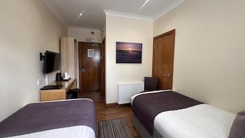 A hotel room with two beds, a desk with a computer, a TV, and a painting on the wall.