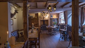A rustic dining area with wooden furniture, a chandelier, and a deer head mounted on the wall. - The Peak Hotel (Hope Valley)