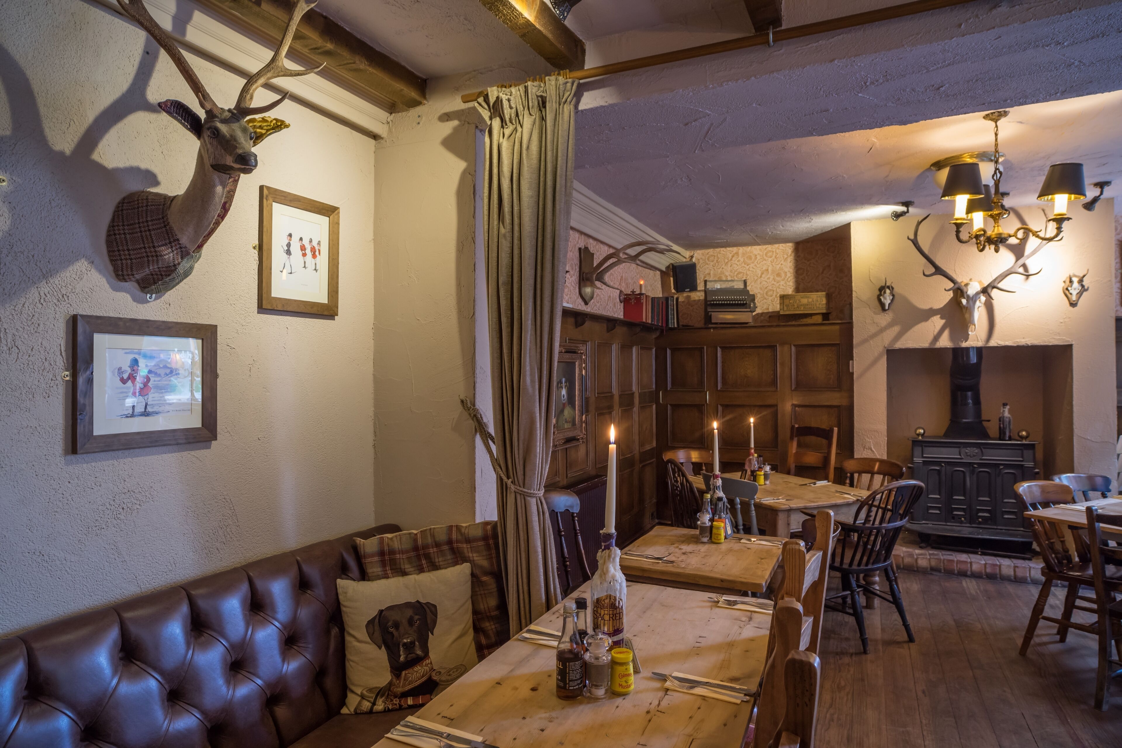 A cozy dining area with a wooden table, leather sofa, and antler decorations.