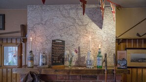 A bar area with a chalkboard menu listing drinks, a candle, and a map on the wall. - The Peak Hotel (Hope Valley)