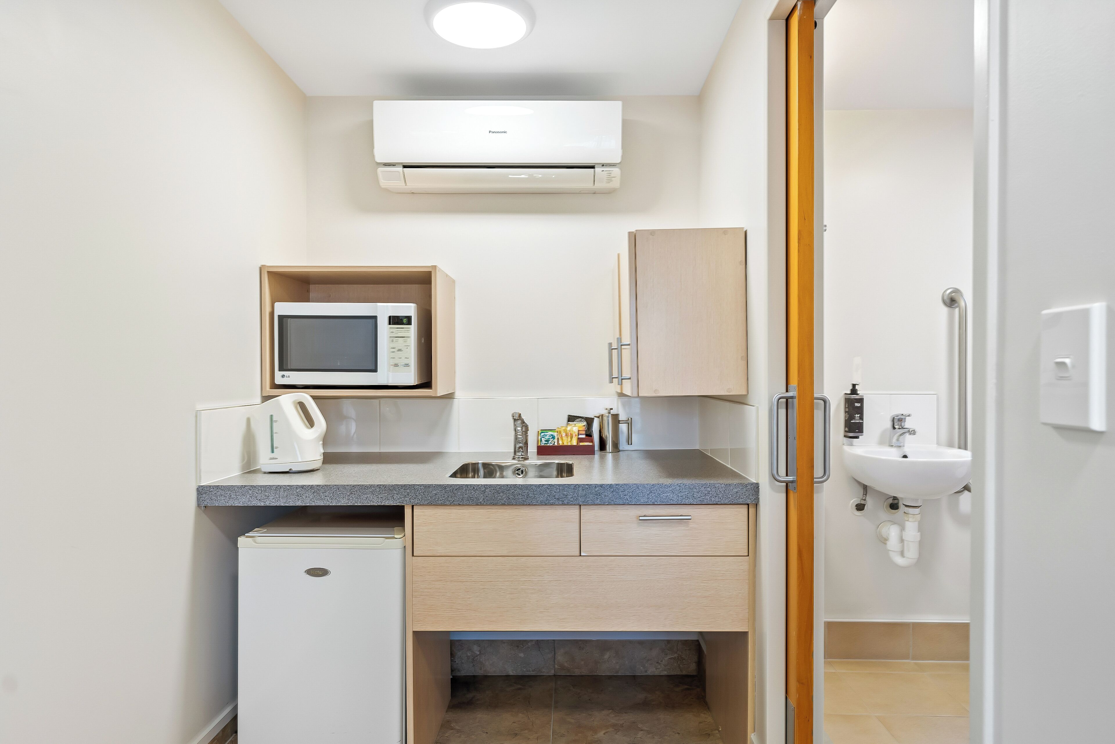 Une cuisine compacte équipée d’un four à micro-ondes, d’un grille-pain, d’un évier et d’un petit réfrigérateur.