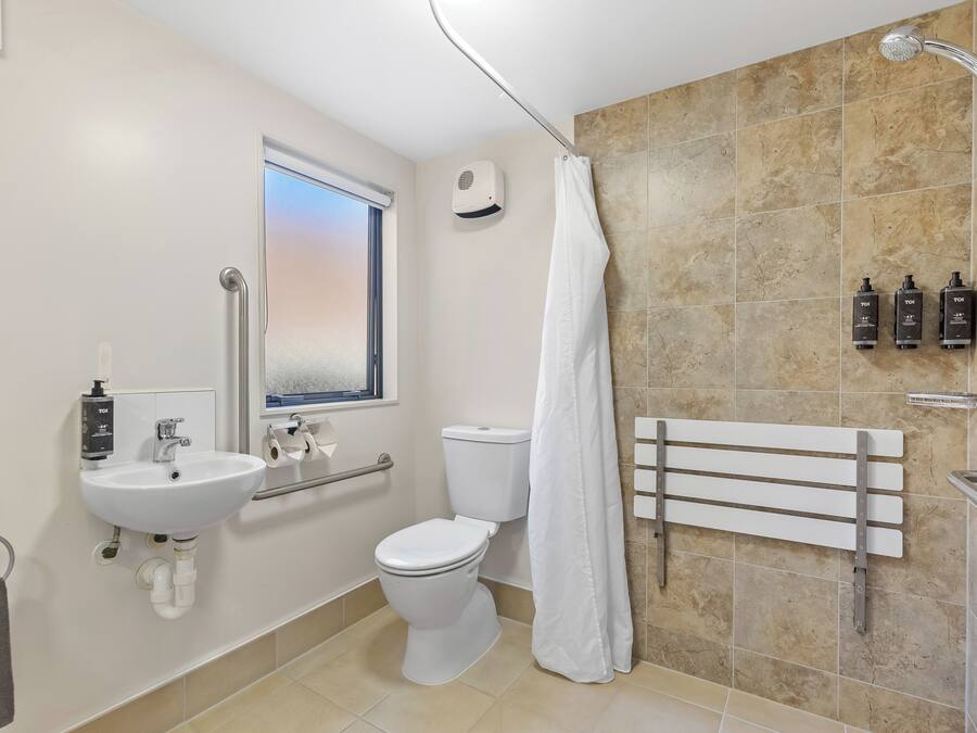 A modern bathroom with a white sink, toilet, and shower.