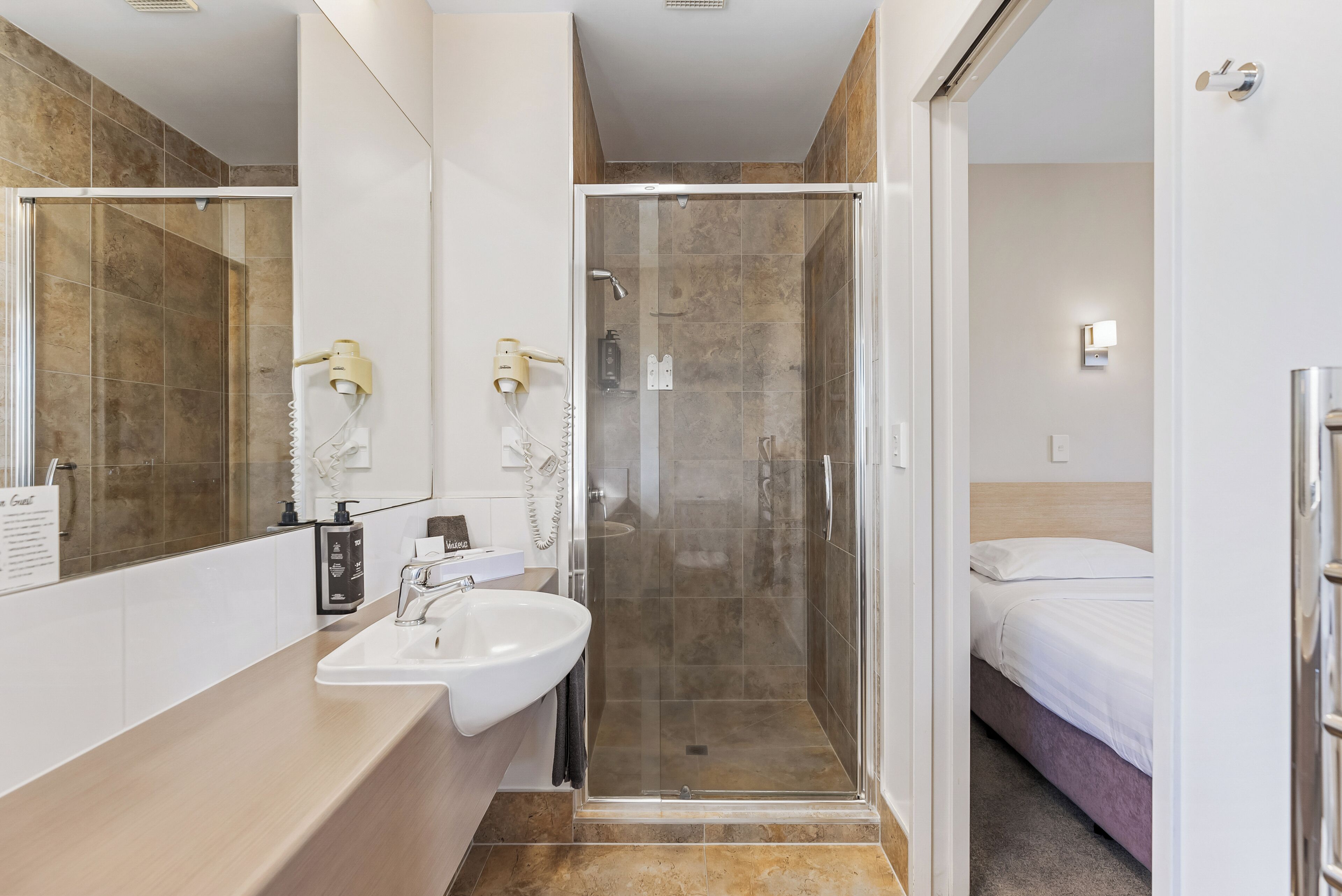 A modern bathroom with a glass-enclosed shower, a sink, and a mirror.
