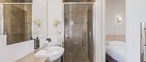 Un baño moderno con cabina de ducha de vidrio, un lavamanos y un espejo.