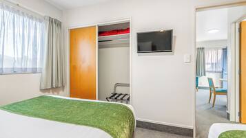 Habitación de hotel con cama, televisor, armario y vista a un comedor.