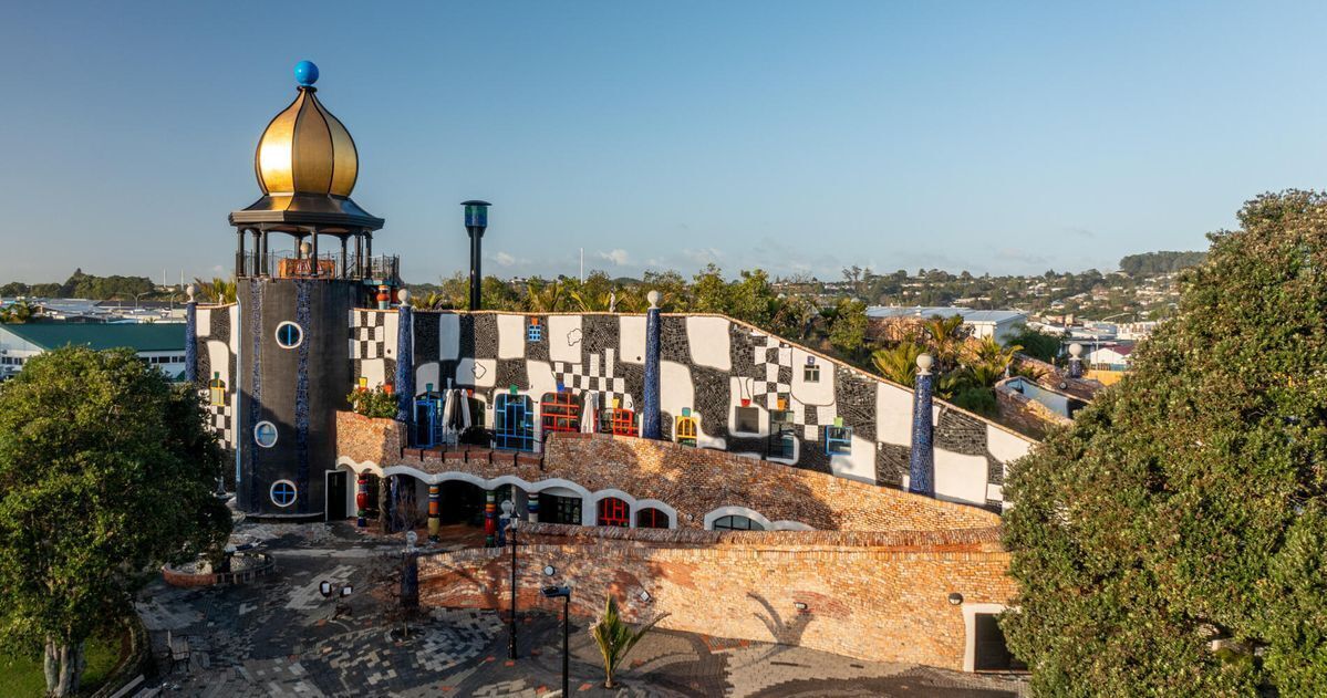A building with a tower, a checkered facade, and a view of a town.