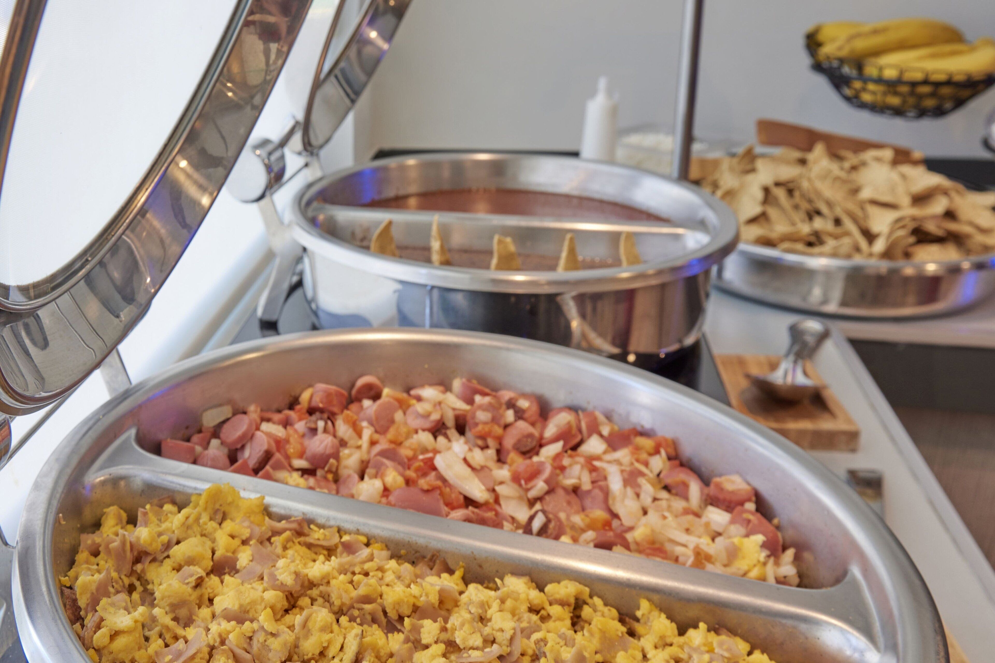 A buffet with scrambled eggs, sausages, and a variety of other dishes.