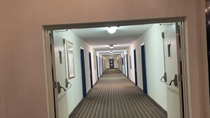 Un couloir d’hôtel avec un panneau indiquant la sortie, des portes et un tapis à motifs.